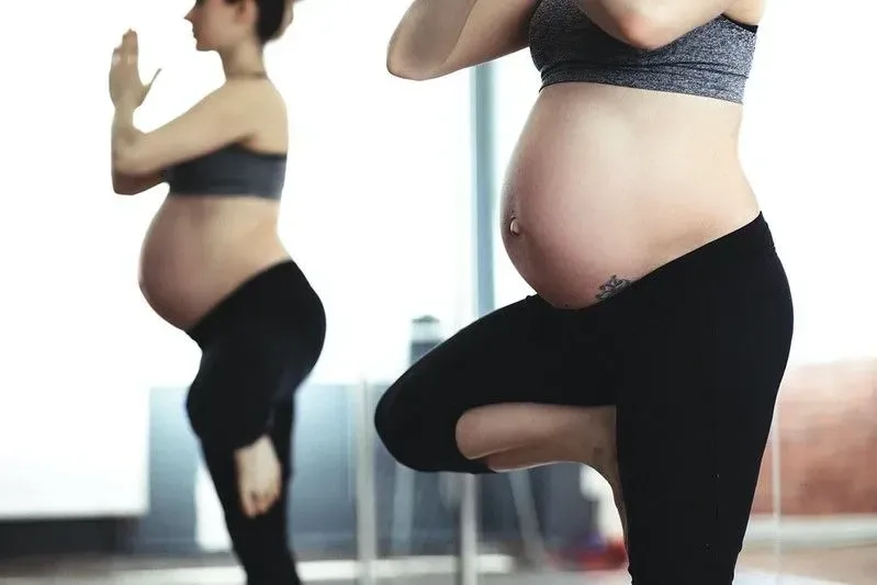 Pregnant woman doing yoga in sportswear. 