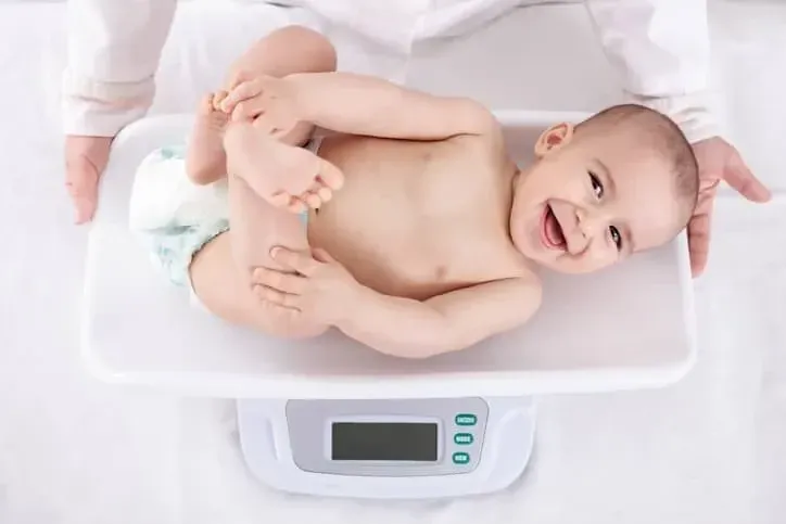 Baby smiling while being weighed. 