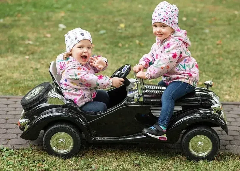Two girls riding in an electric car. 