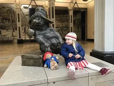 An innocent child sitting alongside Winnie the Pooh's sculpture