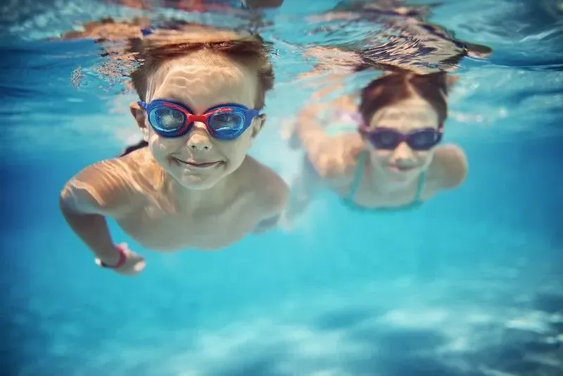 Two children swimming underwater with goggles