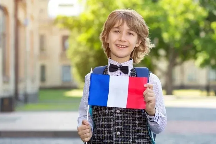 Schoolboy with the flag of France on the background of the school