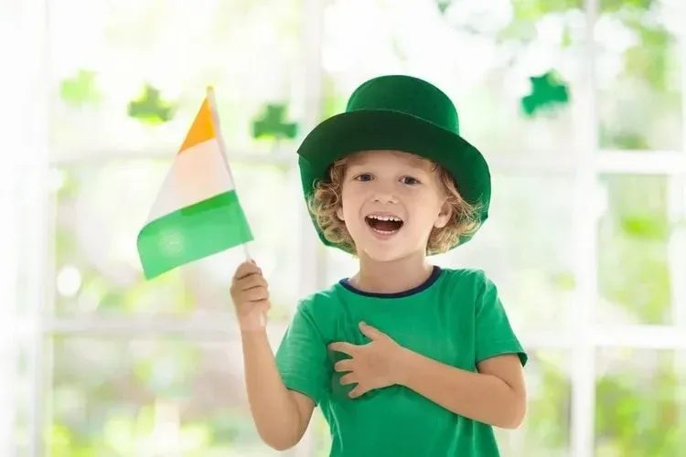 A boy wearing green hat and holding flag of Ireland