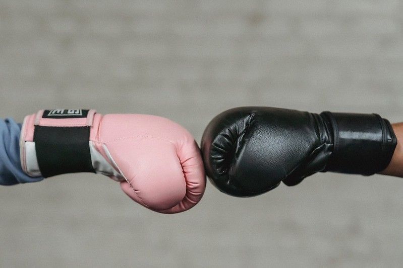 Two boxing gloves, pink and black. 