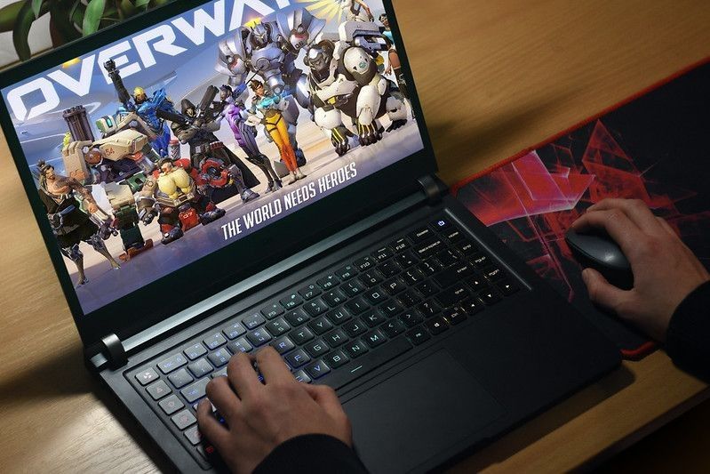 Guy playing Overwatch game on laptop.