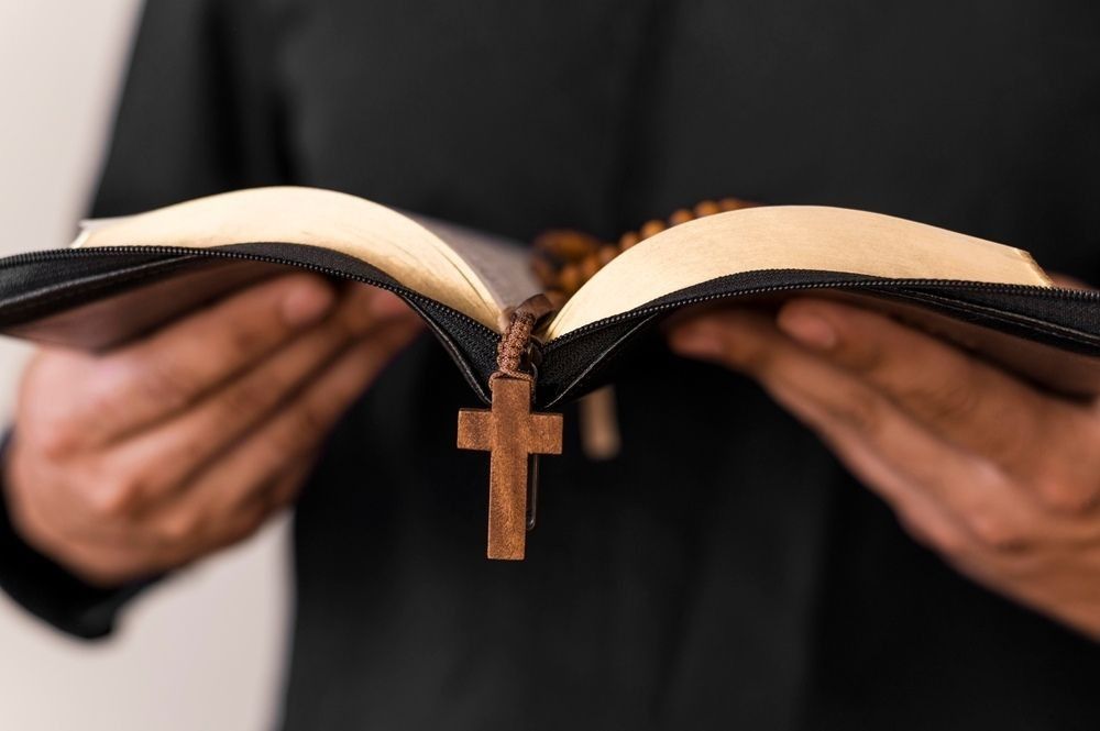 A person holding Holy Bible with Rosary