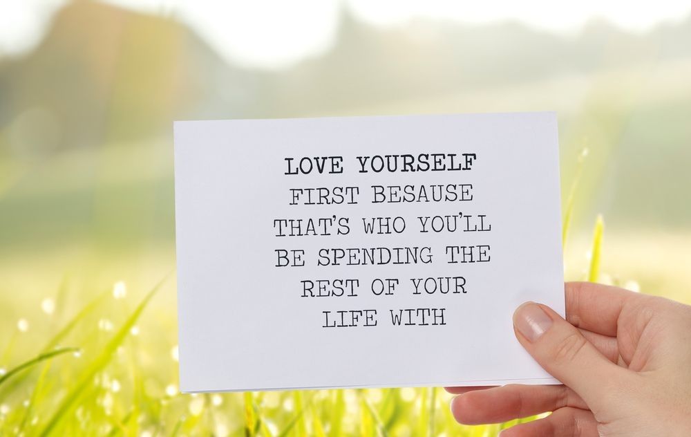 Inspirational Life Quote written on a piece of paper which says "Love yourself first because that's who you'll be spending the rest of your life with". 