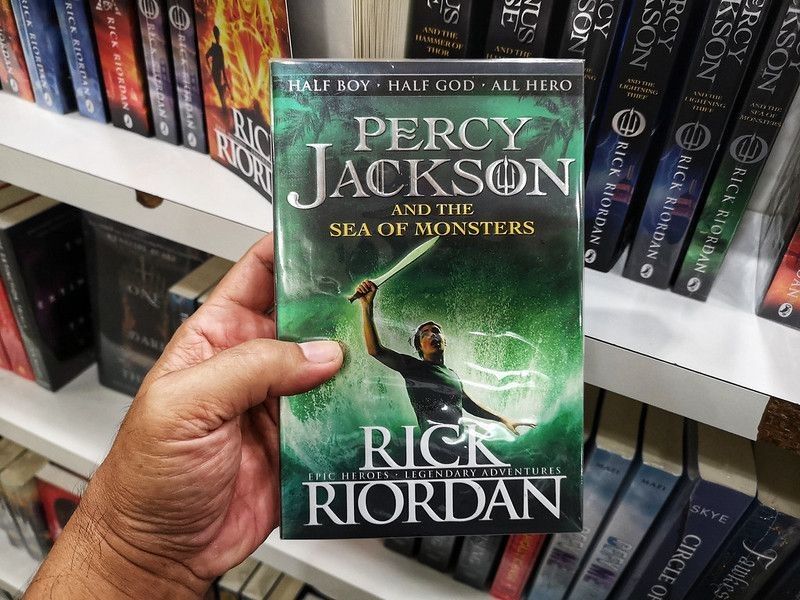 Person holding a RICK RIORDAN book title - PERCY JACKSON AND THE SEA OF MONSTERS