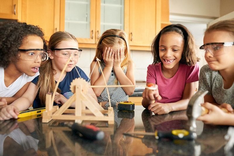 Group of young girls playing with a catapult at home