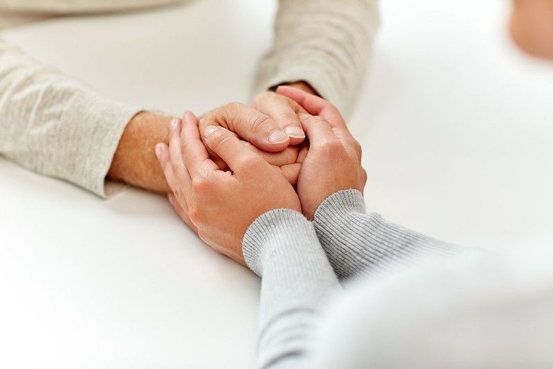 Young lady reassuring a senior person by holding their hands
