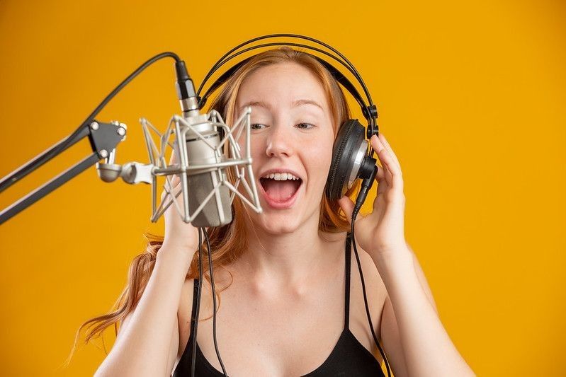 Beautiful redhead woman singing with a condenser silver microphone 
