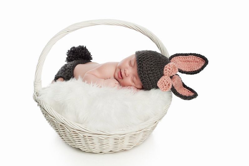 Smiling newborn baby girl wearing a gray and pink bunny costume