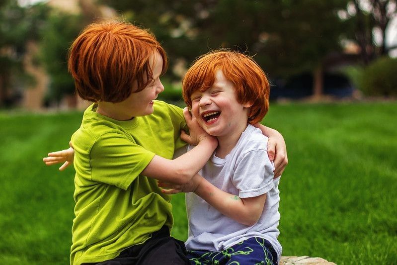 Two young brothers with natural red hair playing outdoor together.