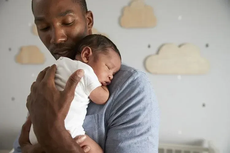 Father holding his newborn sleeping baby in his arms