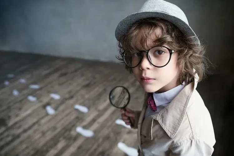 A little boy dressed as a detective holding a magnifying glass