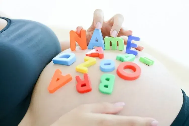 Colorful alphabets scattered on a woman's pregnant belly