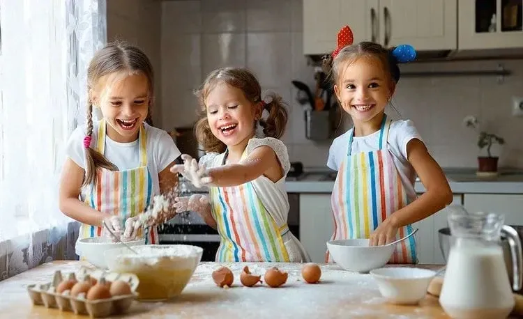 Three girls enjoying while baking cake