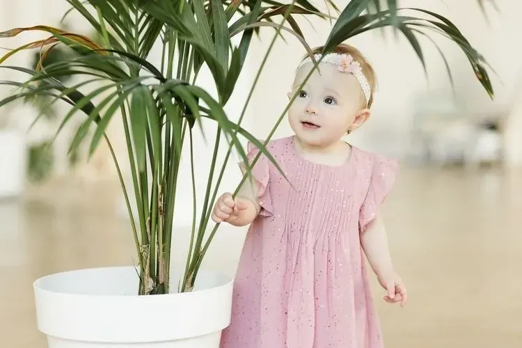 A little girl standing next to a plant