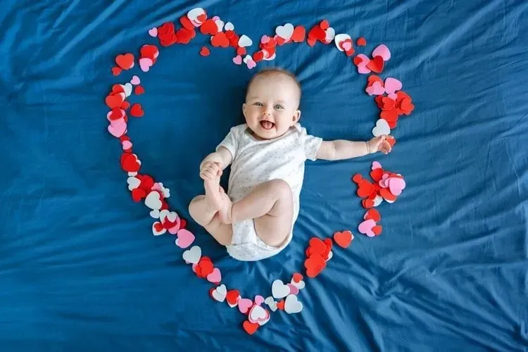 A happy newborn baby lying in middle of a heart