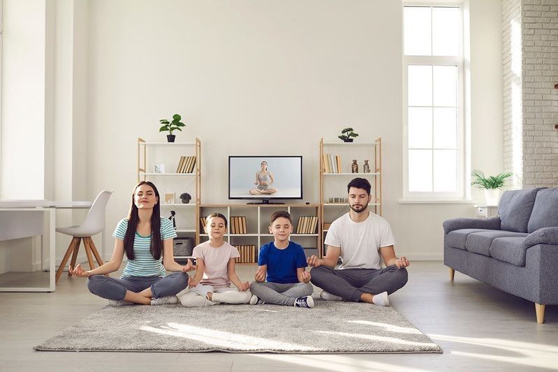 Calm parents and children doing yoga at home