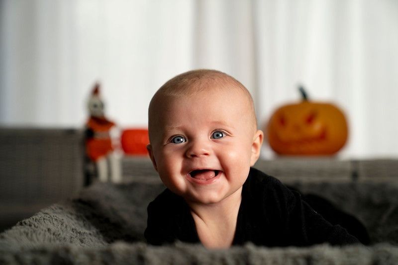 Adorable toddler dressed in black on pumpkin background