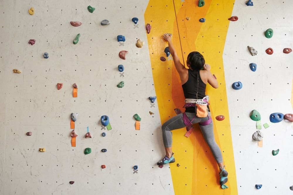 Athletic woman climbing indoors.
