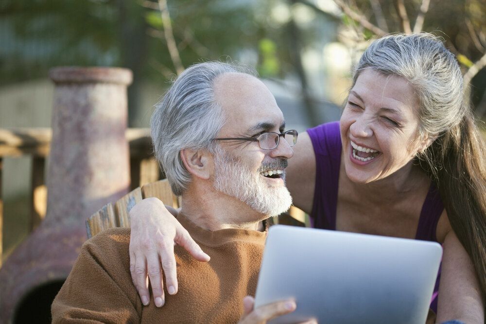 Mature couple laughing while sharing a digital tablet