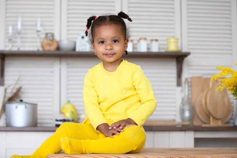 Baby girl wearing yellow clothes sitting in kitchen