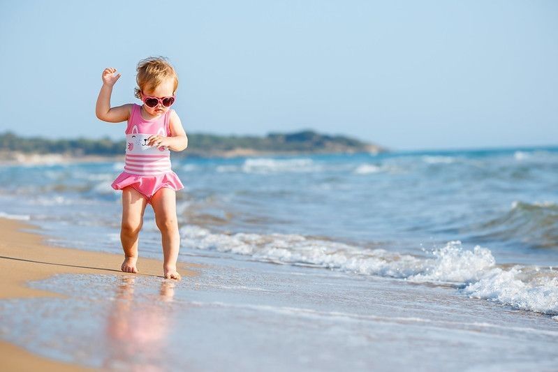 Cute little baby girl running on a beach
