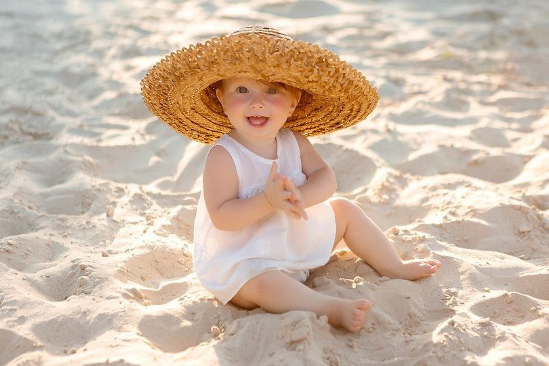 Baby on beach wearing straw hat