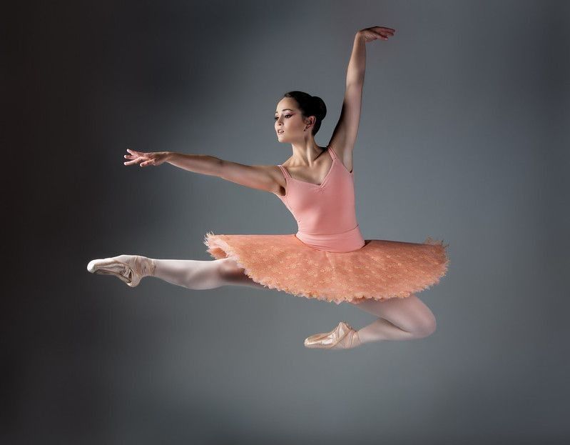 Beautiful female ballet dancer on grey background.