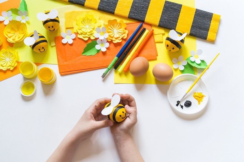 Child  painting an Easter egg yellow bee.