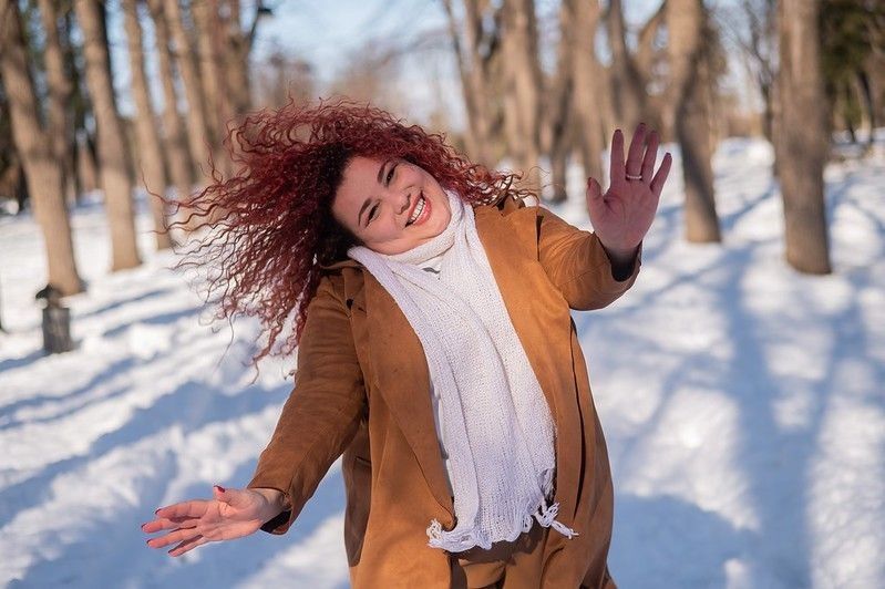 Woman dancing on a walk in the park in winter. 