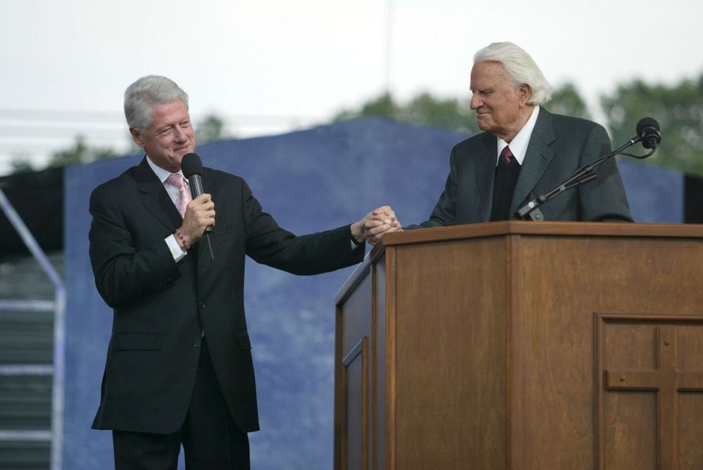 Former U.S. President Bill Clinton (L) speaks with Rev. Billy Graham while on stage at the Greater New York Billy Graham Crusade June 25, 2005 in Flushing, New York.