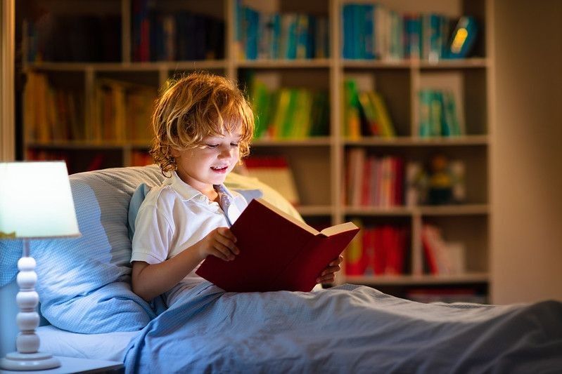 Child reading book in bed