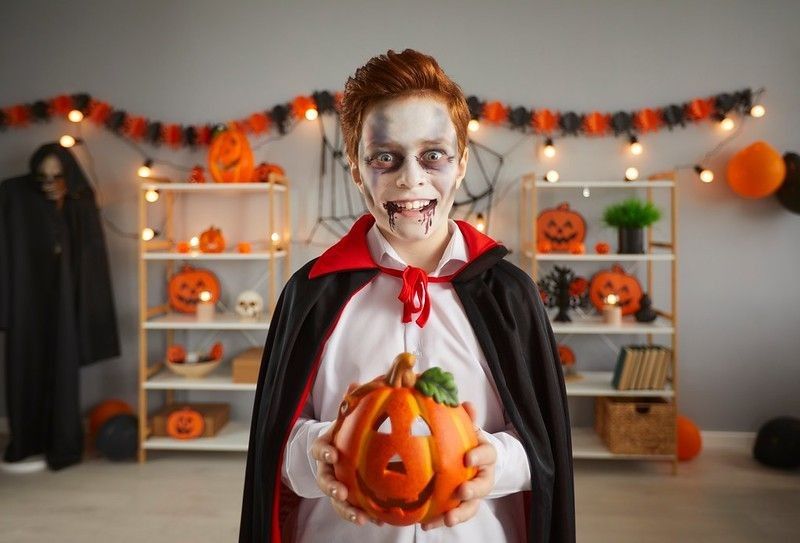 Boy in halloween costume with pumpkin