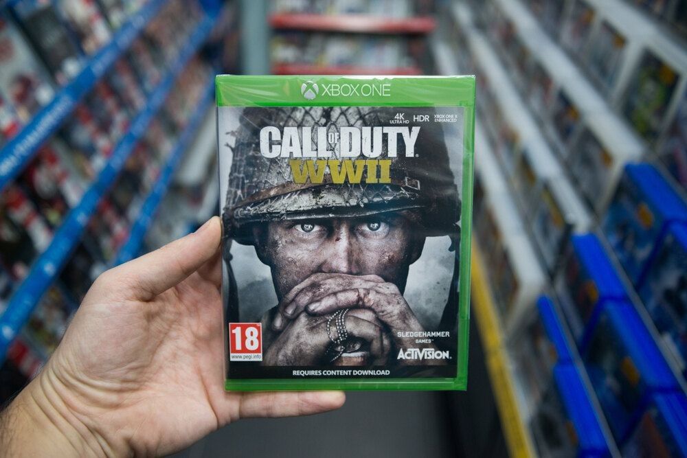 Man holding Call of duty WWII videogame on Microsoft XBOX One console in store