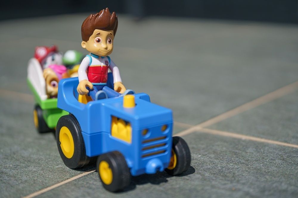 Macro photography of Paw Patrol action figure toys driving car.
