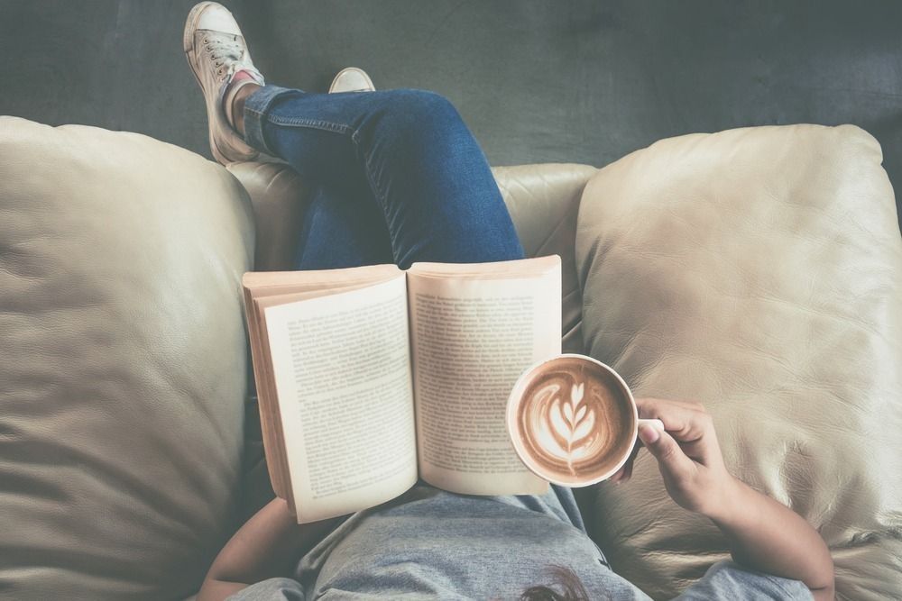 Soft photo of young girl reading a book and drinking coffee