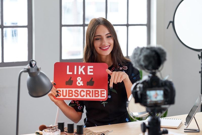 A Youtube content creator shooting with Like and Subscribe board