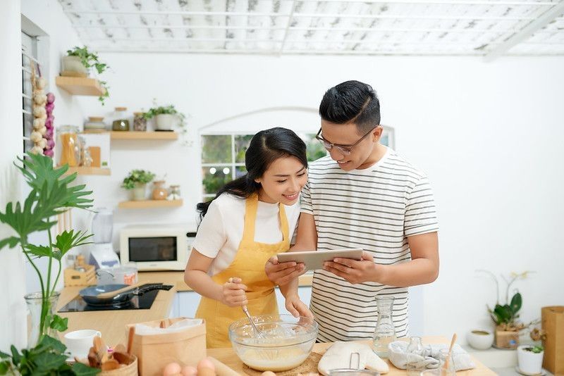 Young asian man and woman together cooking a cake and bread with egg