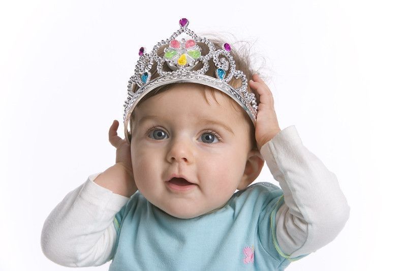 Portrait of a cute baby girl with a toy crown at white background.
