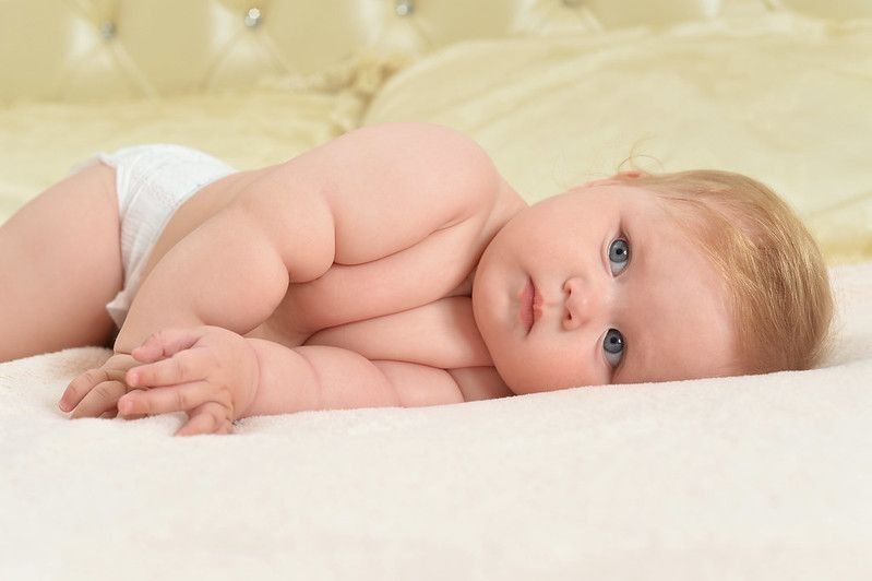 Portrait of cute little baby lying on bed