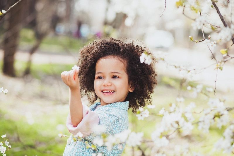 Cute little girl holding flower plucked from the flower tree in a garden.