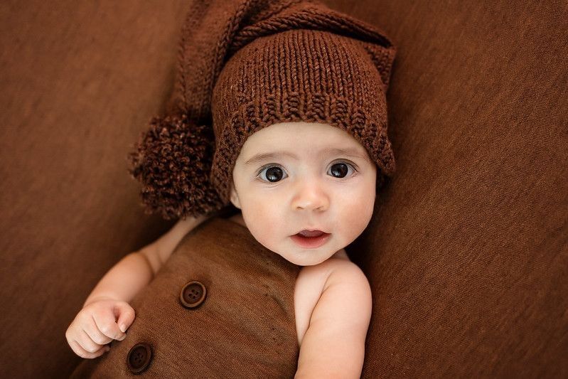 Newborn baby girl wearing warm brown clothes staring at the camera