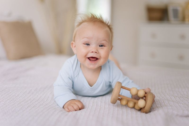 Happy little baby boy playing on bed.