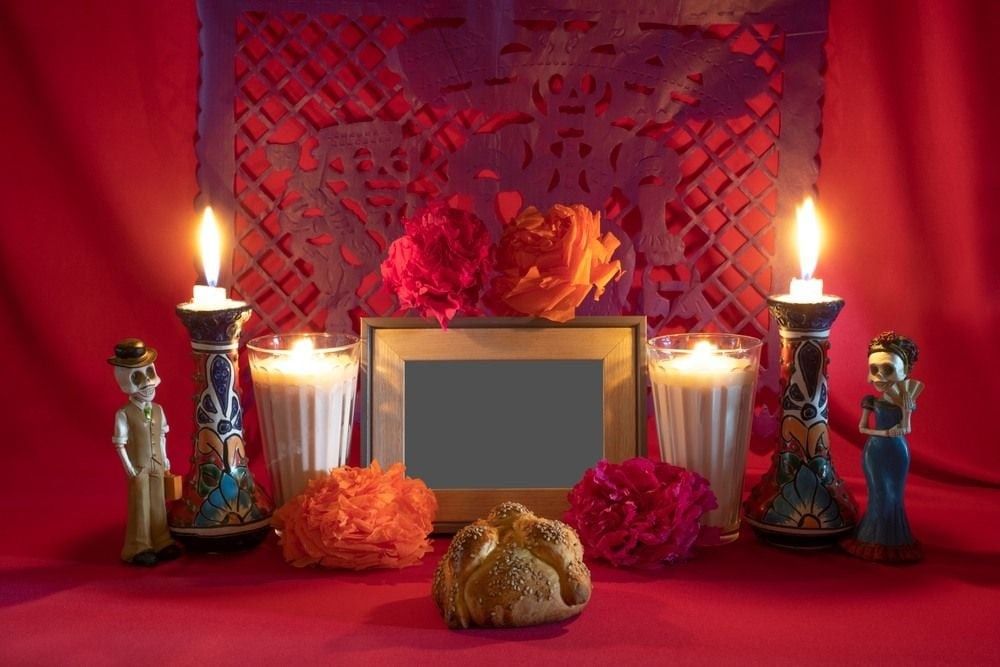 Day of the Dead offering from central Mexico with papel picado, veladoras, photography, flowers and bread of the dead.