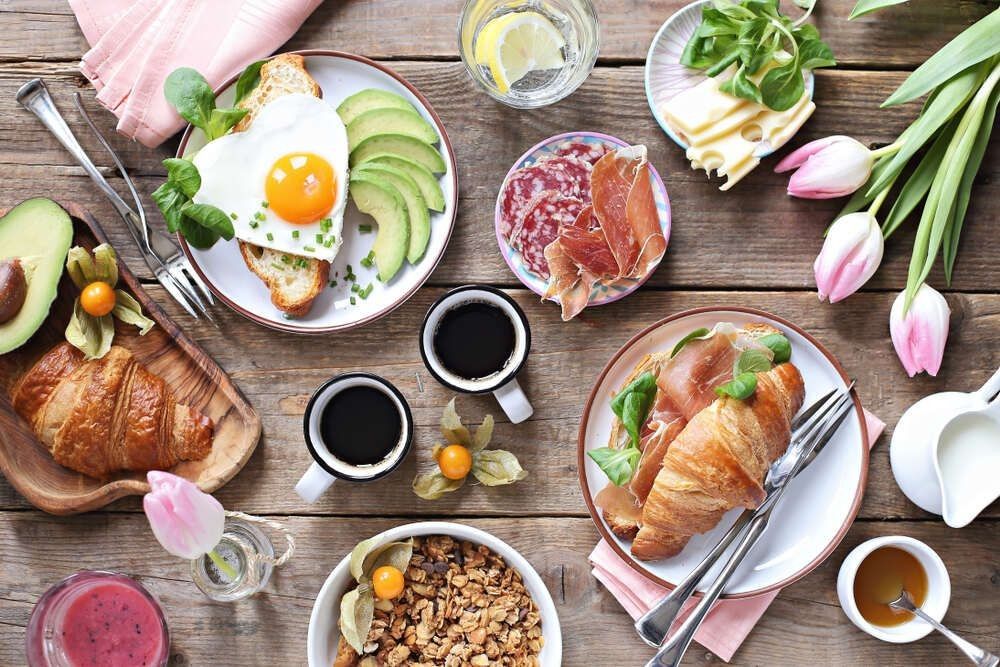 Festive brunch set, meal variety with fried egg, croissant sandwich, granola and smoothie.