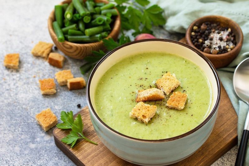 Dietary delicious cream soup of green beans on a light background.