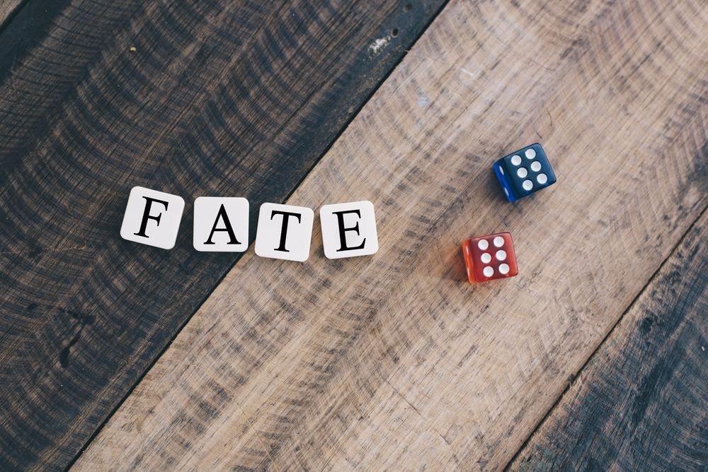 Dice on wooden table with alphabet "FATE".